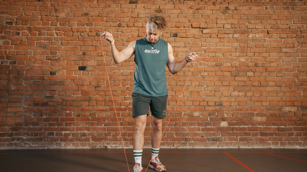 Caucasian man engaging in a jump rope workout in an indoor setting with a brick wall background.